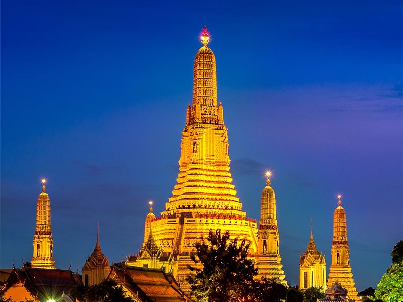 A golden temple spire lit at dusk beside a river
